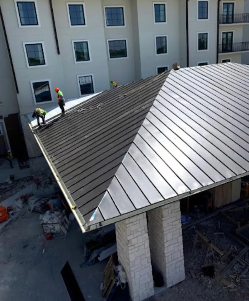 Crew installing standing seam metal roof panels on a commercial project in London